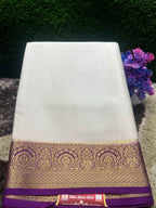 White saree with a purple and gold border on a textured surface with flowers in the background