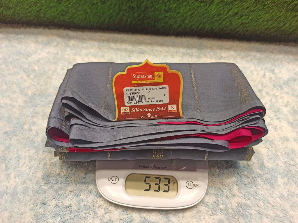 Stack of gray pants with a label on a digital scale showing weight, against a textured surface.