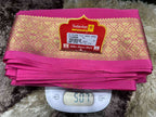 Pink fabric with gold patterns on a scale, featuring Sudarshan brand label.