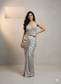 Woman wearing a silver evening gown against a neutral background