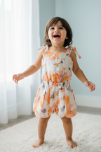Kid wearing orange abstract print romper