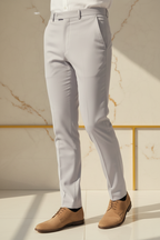 Model in aesthetic pose wearing light grey formal trousers, lower body