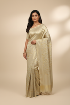 Model wearing champagne ivory gold self-brocade tissue saree