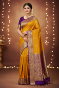 Model wearing mustard yellow Banarasi saree with deep purple gold zari border