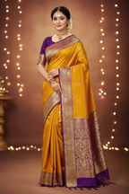 Model wearing mustard yellow Banarasi saree with deep purple gold zari border