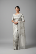 Model wearing pale silver-white tissue saree