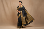 Woman wearing charcoal black saree with antique gold floral vine zari border