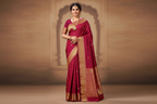 Woman wearing deep magenta silk saree with antique gold zari border