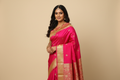 Woman wearing hot pink fuchsia saree with antique gold zari border and pallu
