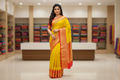 Woman wearing lemon yellow silk saree with red gold zari temple border