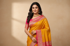 Woman wearing mustard yellow saree with pink gold zari border