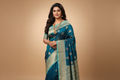 Woman wearing teal blue saree with sky blue gold zari border