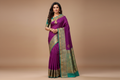 Woman wearing violet purple pinstripe saree with teal green heavy gold zari border